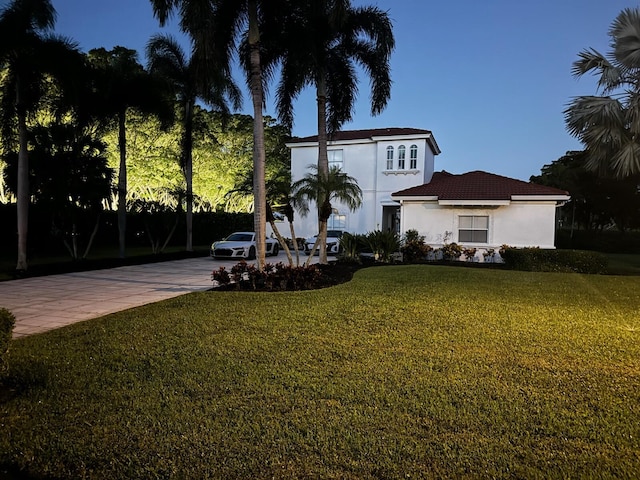 view of front of house with stucco siding, driveway, and a front lawn