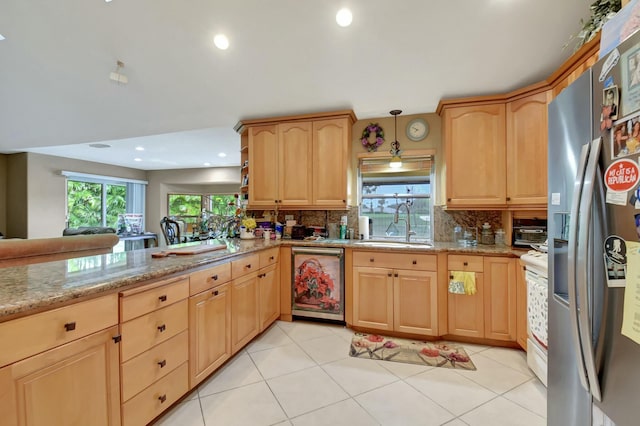 kitchen with appliances with stainless steel finishes, tasteful backsplash, sink, light tile patterned floors, and decorative light fixtures