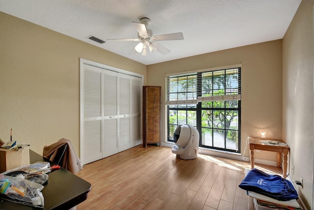 interior space with ceiling fan, a textured ceiling, and light hardwood / wood-style flooring