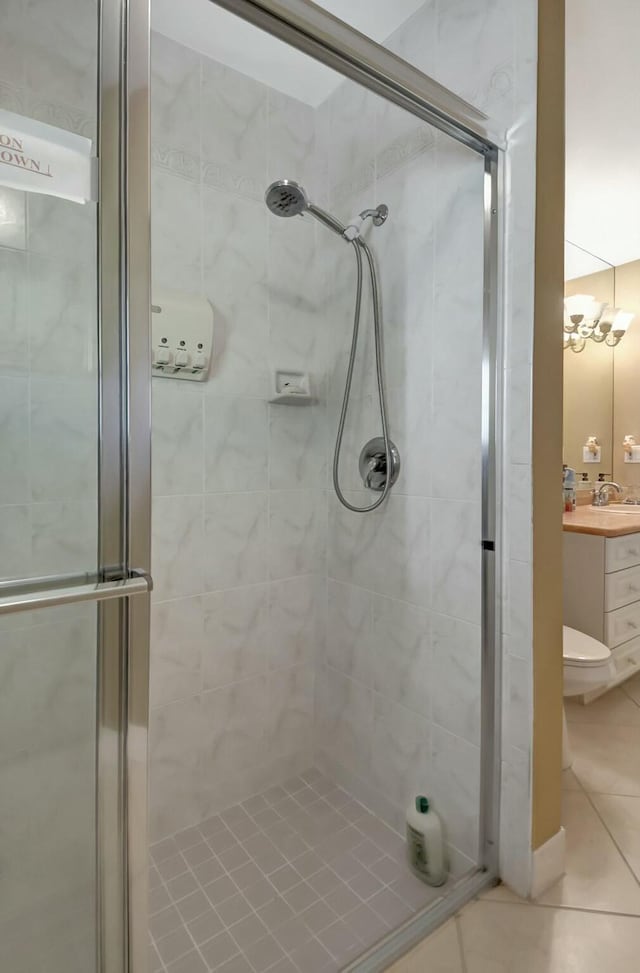 bathroom featuring toilet, vanity, tile patterned floors, and an enclosed shower