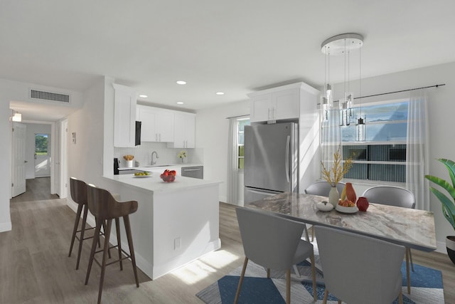 kitchen featuring white cabinetry, dark hardwood / wood-style flooring, decorative light fixtures, a kitchen island, and appliances with stainless steel finishes