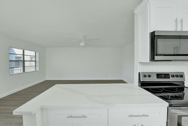 kitchen featuring light stone counters, stainless steel electric stove, ceiling fan, hardwood / wood-style floors, and white cabinetry