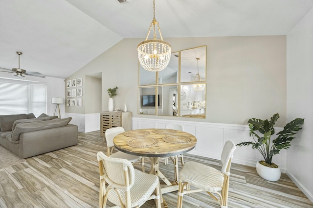 dining space featuring ceiling fan with notable chandelier, light hardwood / wood-style floors, and lofted ceiling