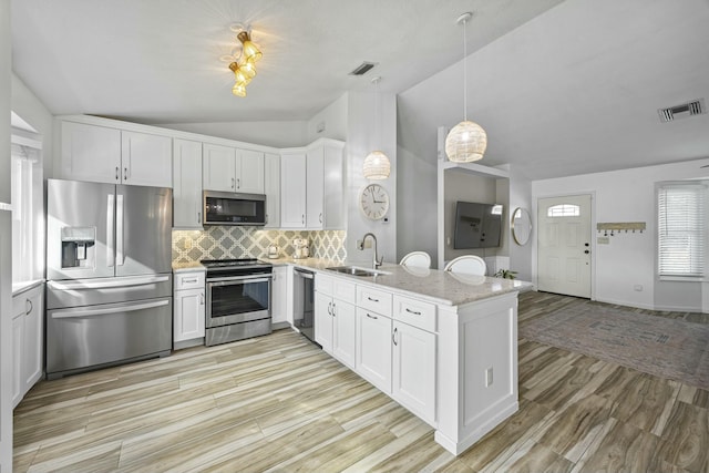 kitchen with white cabinetry, sink, stainless steel appliances, light hardwood / wood-style flooring, and lofted ceiling