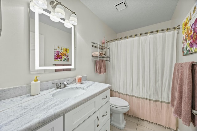 bathroom featuring tile patterned floors, vanity, toilet, and a textured ceiling