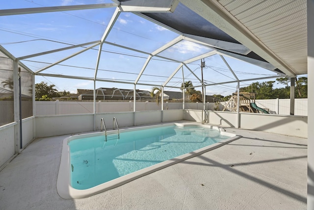 view of pool featuring glass enclosure, a playground, and a patio