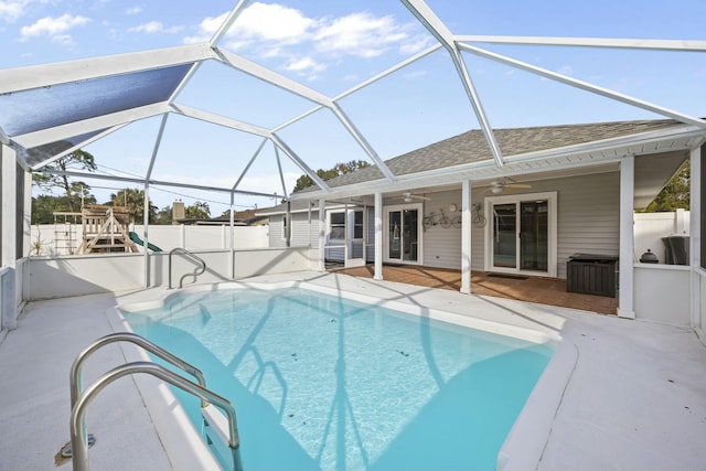 view of swimming pool with ceiling fan, a patio area, and glass enclosure