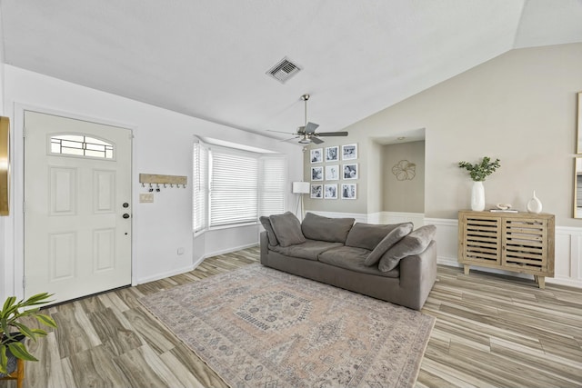 living room featuring ceiling fan, light hardwood / wood-style flooring, and vaulted ceiling