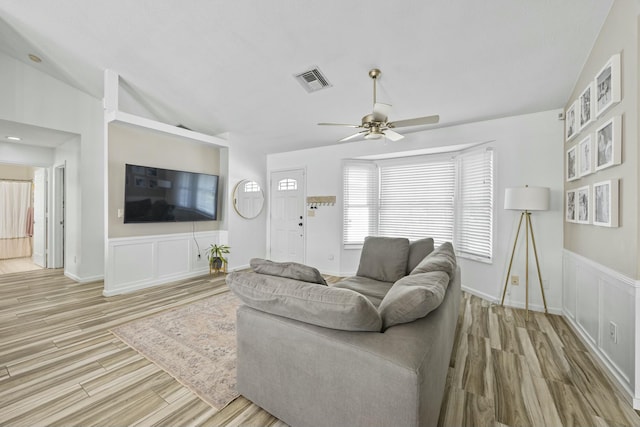 living room featuring ceiling fan, light wood-type flooring, and vaulted ceiling