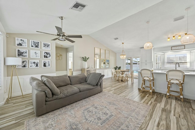 living room featuring light hardwood / wood-style flooring, ceiling fan, lofted ceiling, and sink