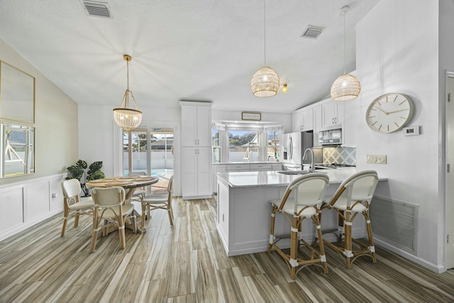 kitchen featuring white cabinets, lofted ceiling, appliances with stainless steel finishes, and an inviting chandelier