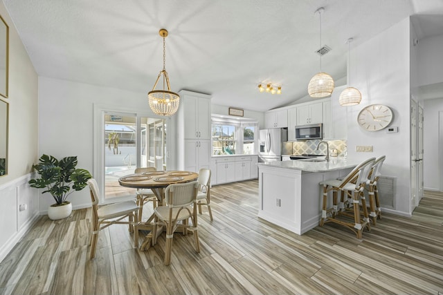 kitchen featuring kitchen peninsula, white cabinets, stainless steel appliances, and lofted ceiling