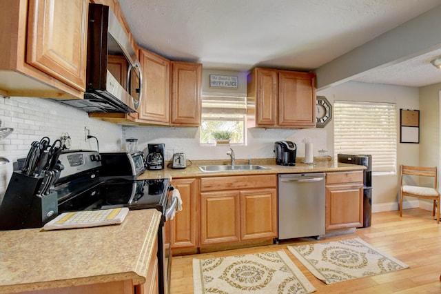 kitchen with light hardwood / wood-style floors, sink, and appliances with stainless steel finishes