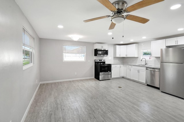 kitchen featuring backsplash, stainless steel appliances, sink, white cabinets, and light hardwood / wood-style floors