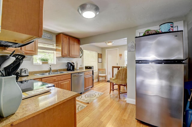 kitchen with decorative backsplash, sink, stainless steel appliances, and light wood-type flooring