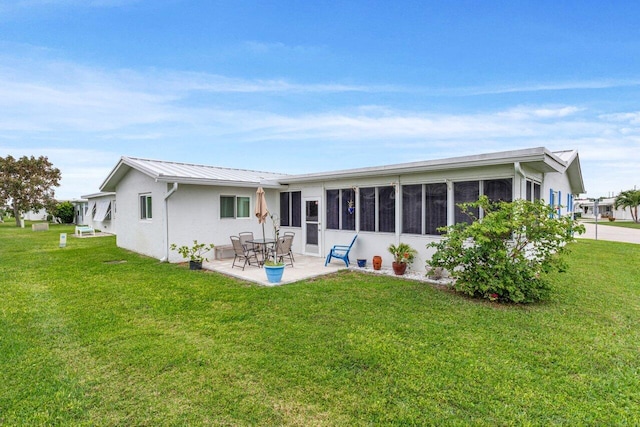 rear view of house featuring a sunroom, a patio area, and a lawn