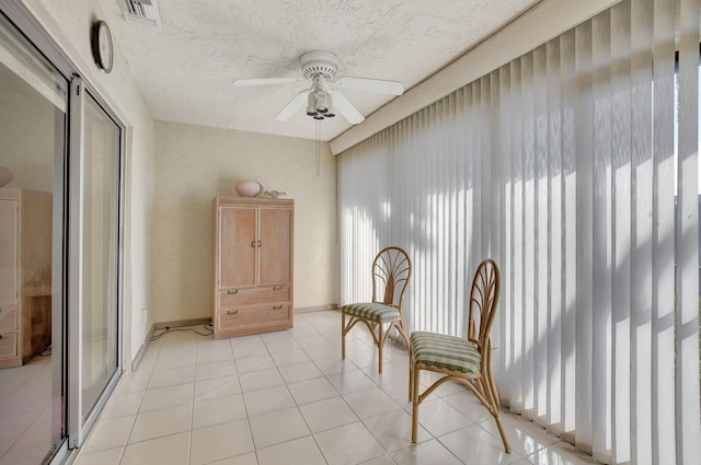 sitting room featuring ceiling fan, light tile patterned floors, and a textured ceiling