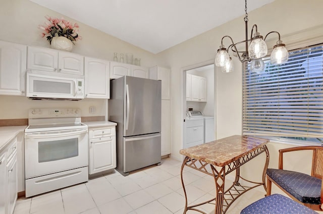 kitchen with washer and clothes dryer, pendant lighting, white appliances, vaulted ceiling, and white cabinetry