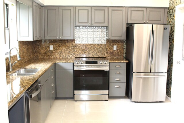 kitchen featuring light stone countertops, light tile patterned floors, appliances with stainless steel finishes, ceiling fan, and sink