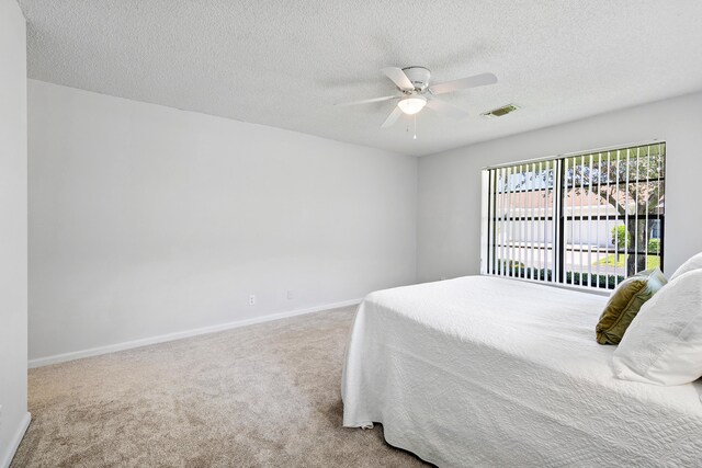 carpeted bedroom with ceiling fan, a textured ceiling, and access to exterior