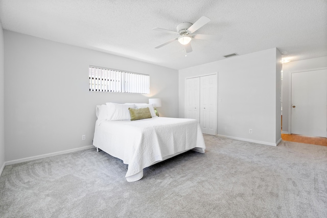 bedroom with a textured ceiling, ceiling fan, a closet, and carpet