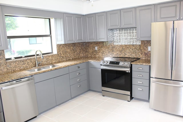 kitchen with tasteful backsplash, appliances with stainless steel finishes, gray cabinetry, and a sink