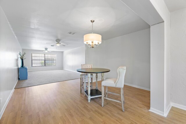 dining area featuring ceiling fan with notable chandelier, french doors, and light hardwood / wood-style floors