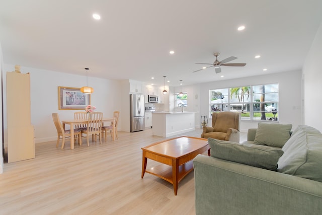 living room featuring ceiling fan, light hardwood / wood-style floors, and sink