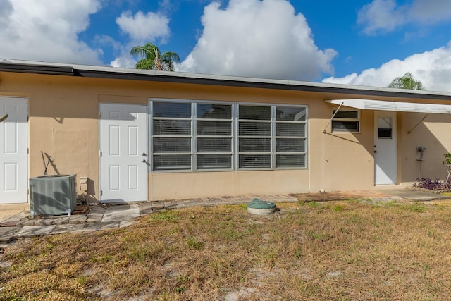 rear view of property featuring central air condition unit and a lawn