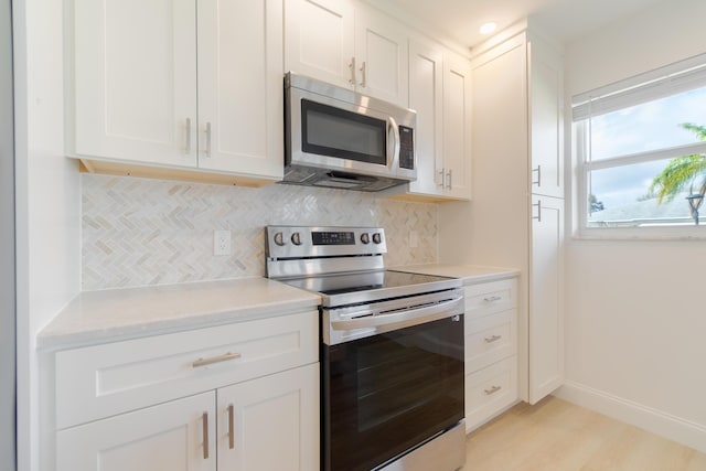 kitchen featuring white cabinetry, appliances with stainless steel finishes, tasteful backsplash, and light wood-type flooring