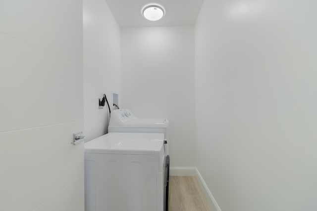 clothes washing area featuring light hardwood / wood-style flooring and washing machine and clothes dryer