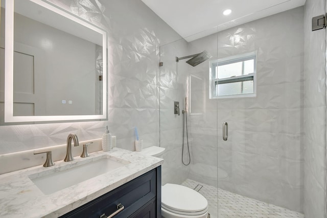 bathroom with backsplash, vanity, tile walls, toilet, and a shower with shower door