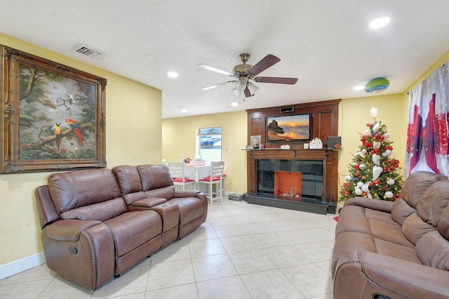 tiled living room with ceiling fan and a tile fireplace