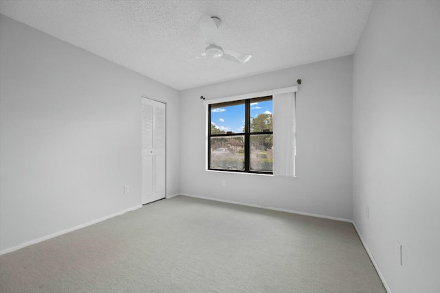 empty room with ceiling fan, light carpet, and a textured ceiling