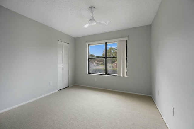 empty room featuring ceiling fan, carpet floors, and a textured ceiling