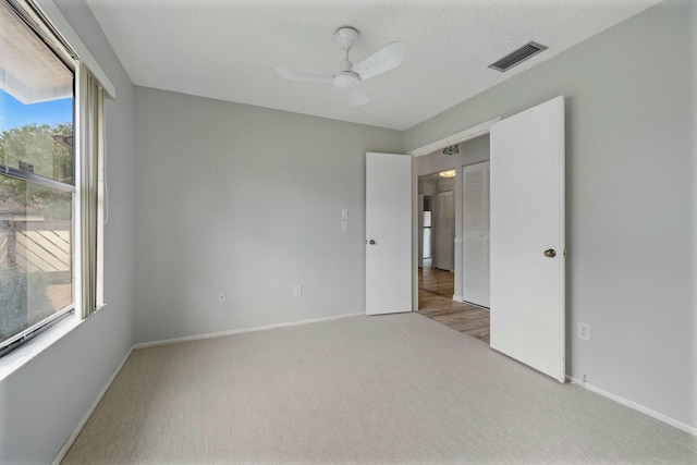 carpeted empty room with a wealth of natural light and ceiling fan