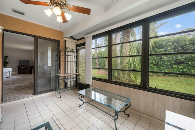 unfurnished sunroom featuring beamed ceiling and ceiling fan