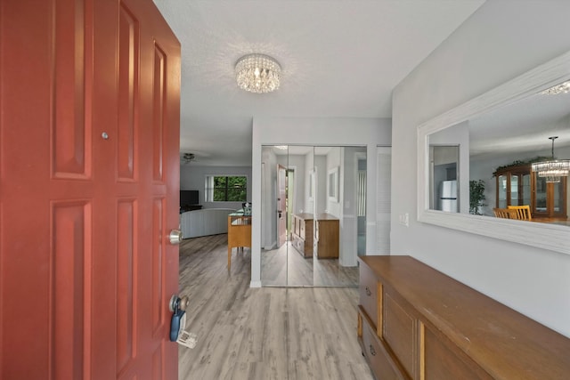 entrance foyer featuring ceiling fan with notable chandelier, a textured ceiling, and light wood-type flooring