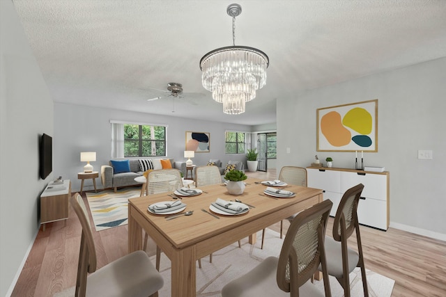 dining space with ceiling fan with notable chandelier, light hardwood / wood-style floors, and a textured ceiling