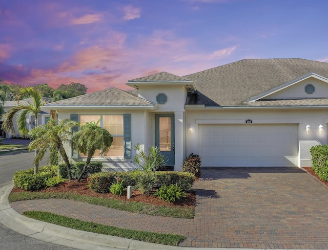 view of front of house with a garage, decorative driveway, and stucco siding