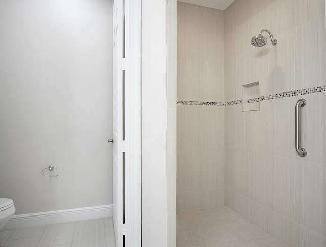 bathroom with toilet and a tile shower