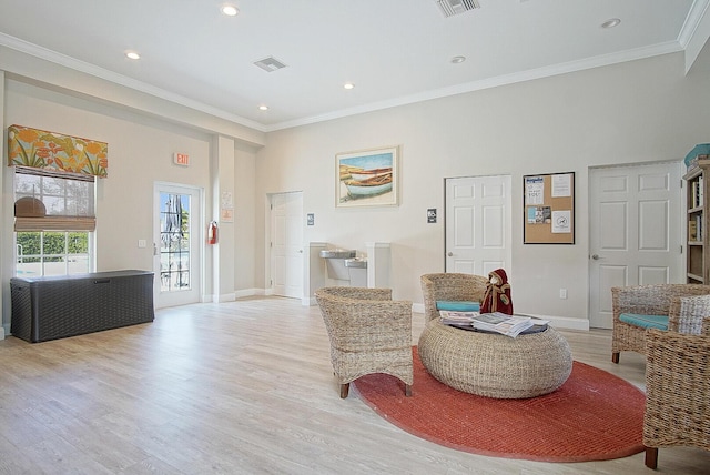 living area with light wood-type flooring, ornamental molding, and a high ceiling