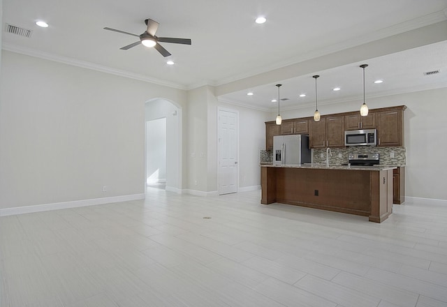 kitchen featuring decorative backsplash, stainless steel appliances, ceiling fan, pendant lighting, and an island with sink