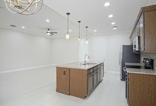 kitchen with light stone countertops, sink, stainless steel appliances, a center island with sink, and ceiling fan with notable chandelier