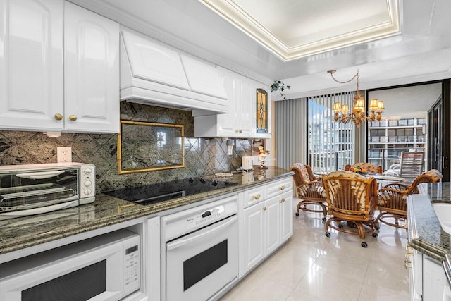 kitchen featuring backsplash, white appliances, custom range hood, and a tray ceiling