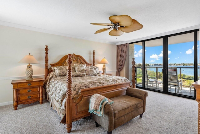 carpeted bedroom with access to exterior, expansive windows, ceiling fan, crown molding, and a water view