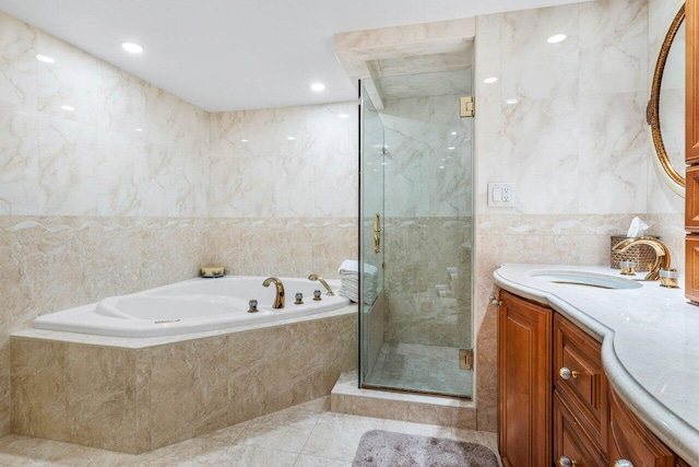 bathroom with tile patterned flooring, vanity, tile walls, and independent shower and bath