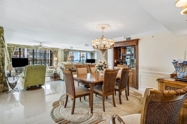 tiled dining space featuring a textured ceiling, ceiling fan with notable chandelier, and ornamental molding