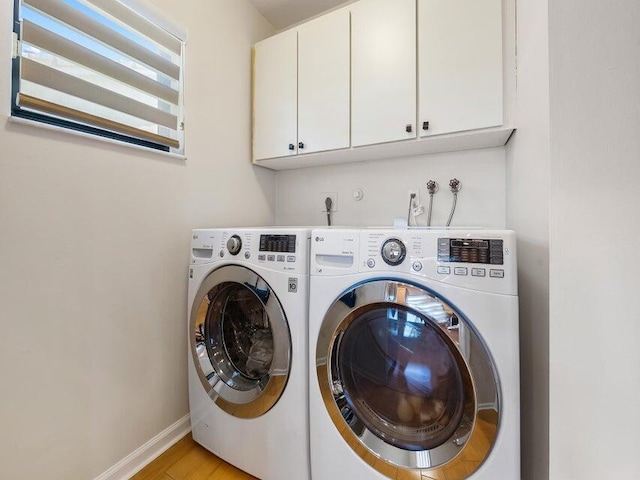 washroom with washing machine and clothes dryer, cabinets, and light hardwood / wood-style floors