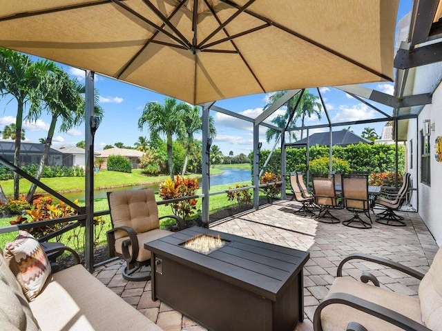 view of patio featuring a water view, glass enclosure, and an outdoor fire pit